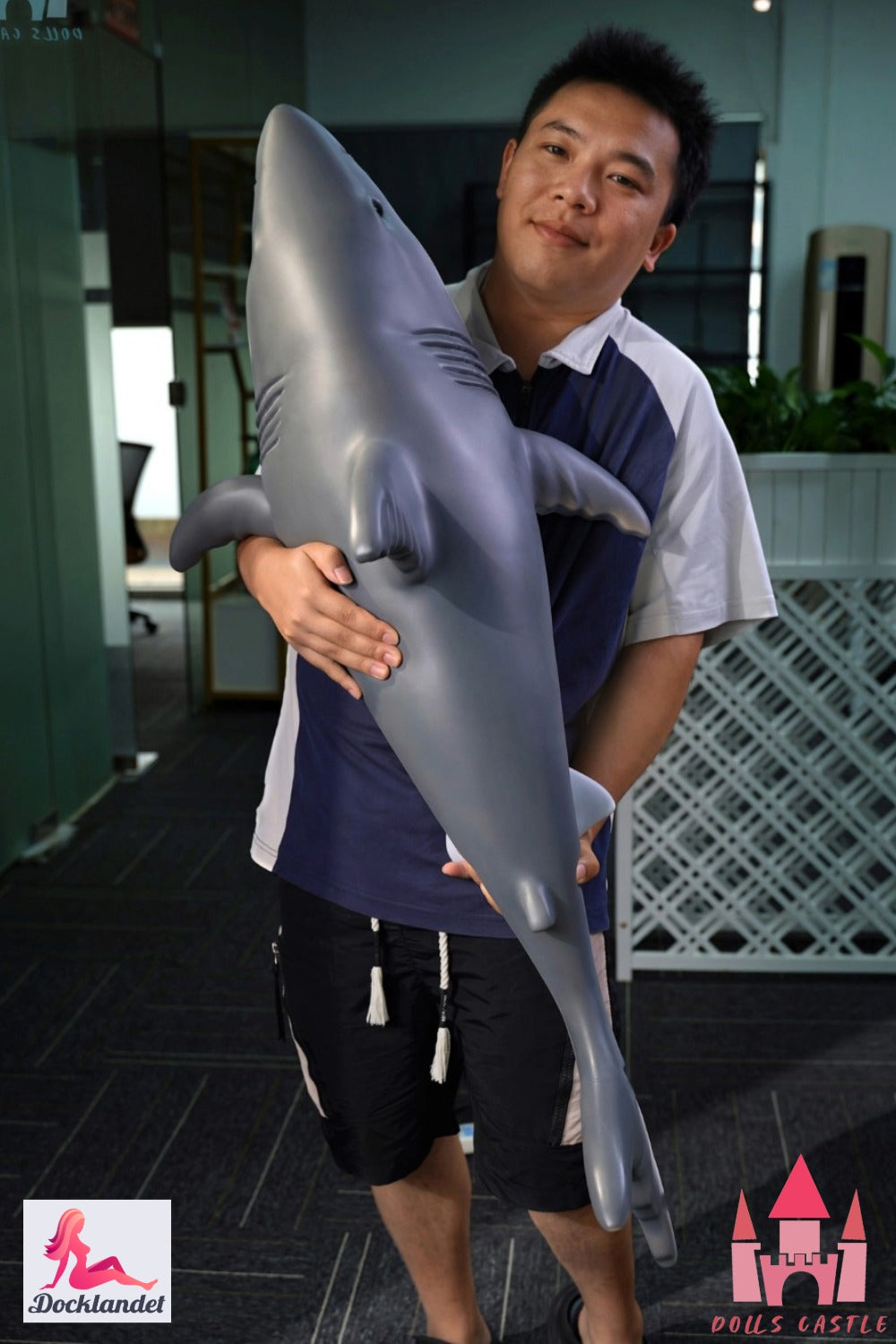 Shark Doll 110 cm holdes i armene for at vise størrelse og proportioner, realistisk hajdesign med grå top og hvid bund.