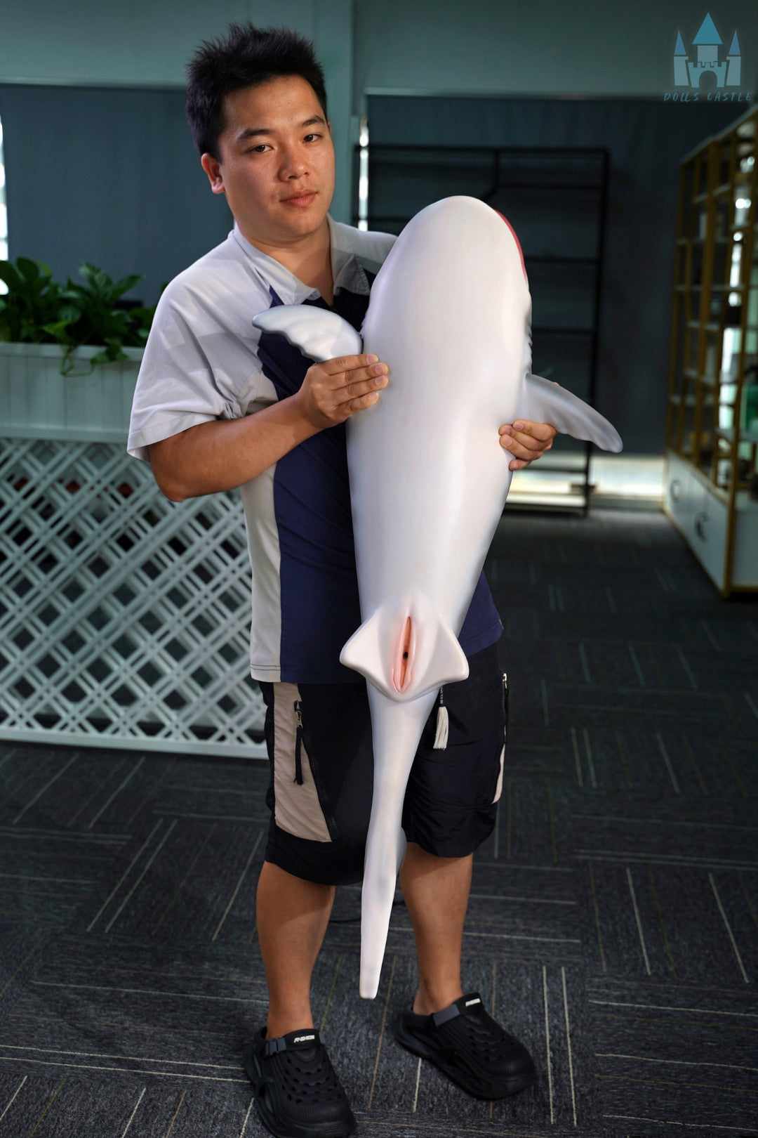 Shark Doll 110 cm holdes i armene for at vise størrelse og proportioner, realistisk hajdesign med grå top og hvid bund.